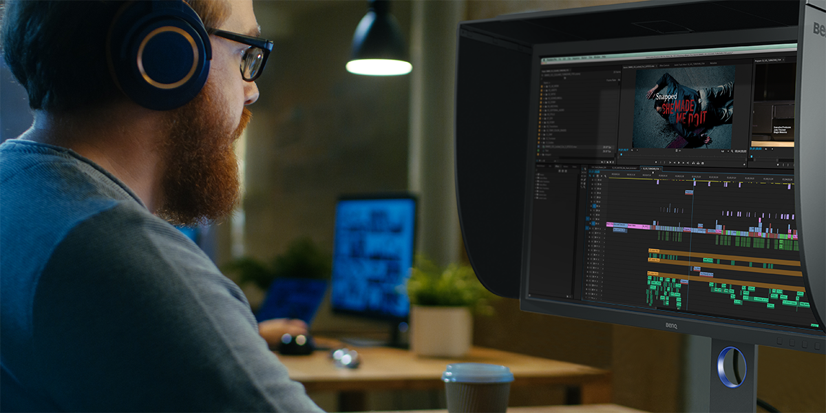 A video expert sitting in front of a professional thunderbolt monitor on his editing workflow 