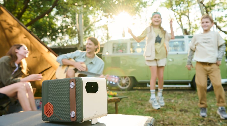 Family having a great time with a portable projector by a van