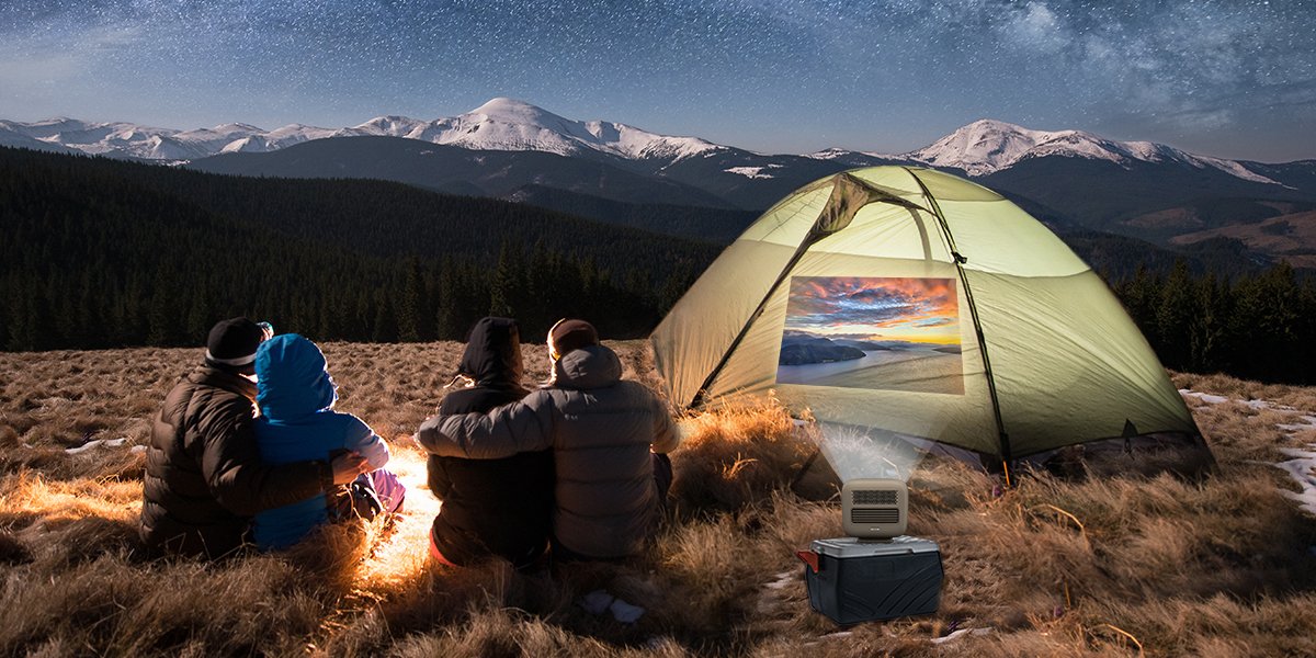 4 friends camping in the wild and watching movies on an outdoor projector for entertainment
