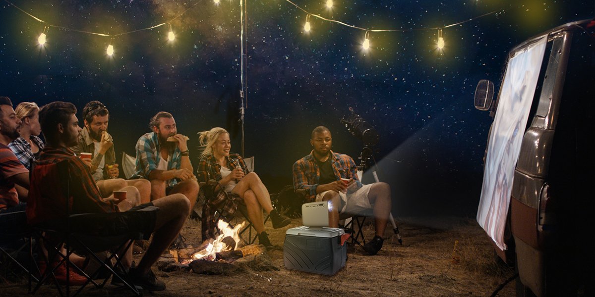 a group of friends watch movies on a camper RV with a portable projector