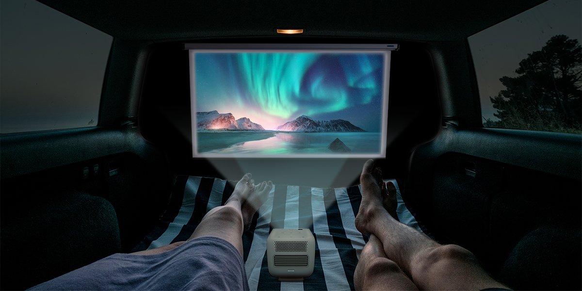 two people watching movies on a portable projector inside a camper RV or campervan