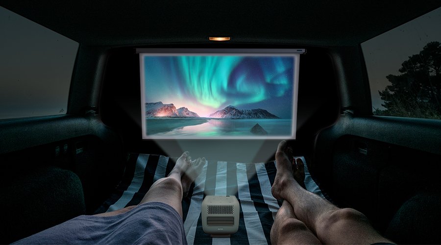 Two people watching movies on a portable projector inside of a camper RV or campervan