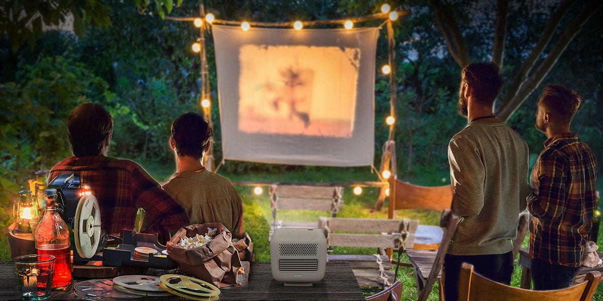 4 friends gather in the backyard and enjoy outdoor cinema with a portable projector