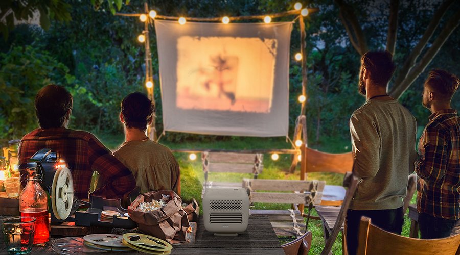 4 friends gather in the garden and enjoy outdoor cinema with a portable projector