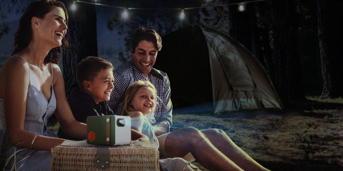 family having a great time with a portable projector at the campsite