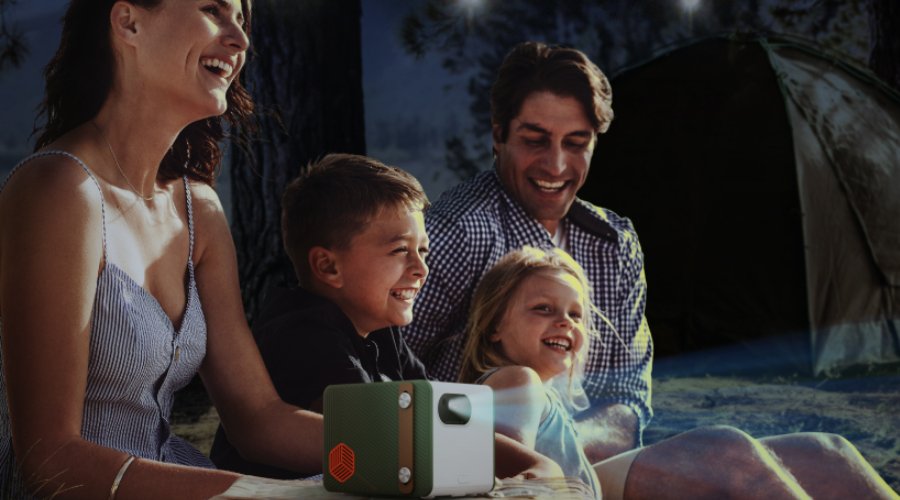 family having a great time with a portable projector at a campsite