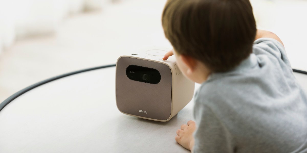 a kid is pressing the button on a portable mini projector 