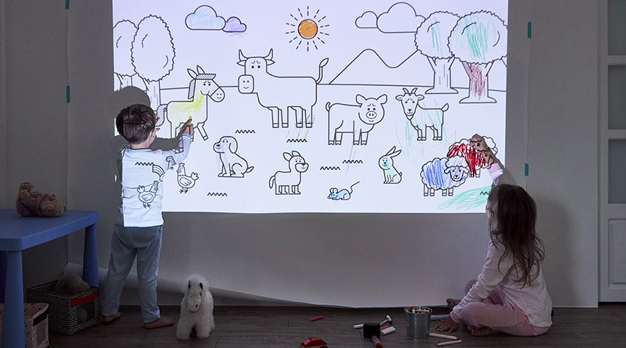 Two kids drawing on a big wall with the help of a portable projector