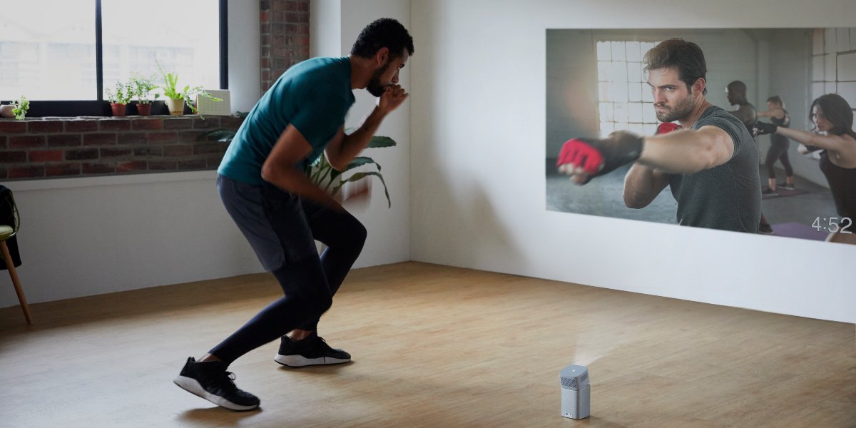a guy is doing boxing exercise at home to a portable projector 
