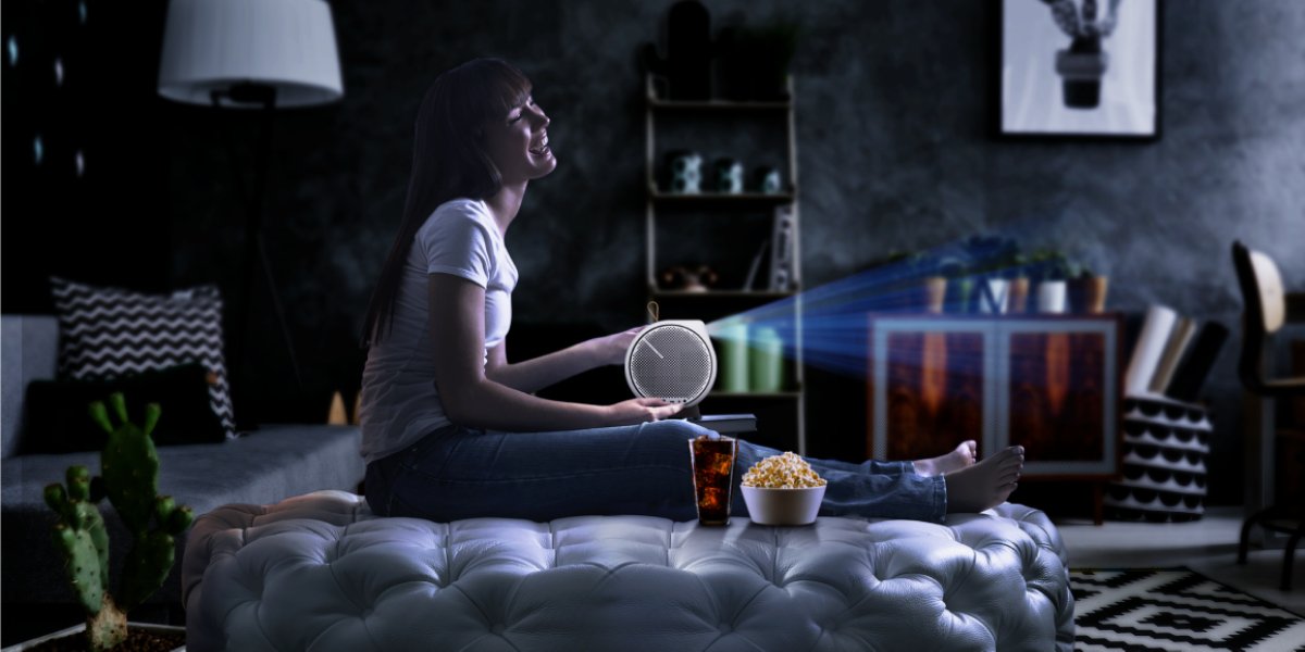 A young lady enjoys her home cinema with a portable projector